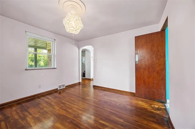 an empty room with wooden floor mirror and windows