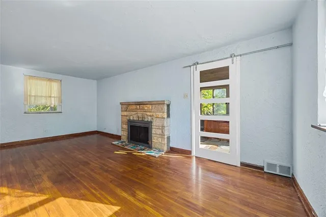 an empty room with wooden floor fireplace and windows