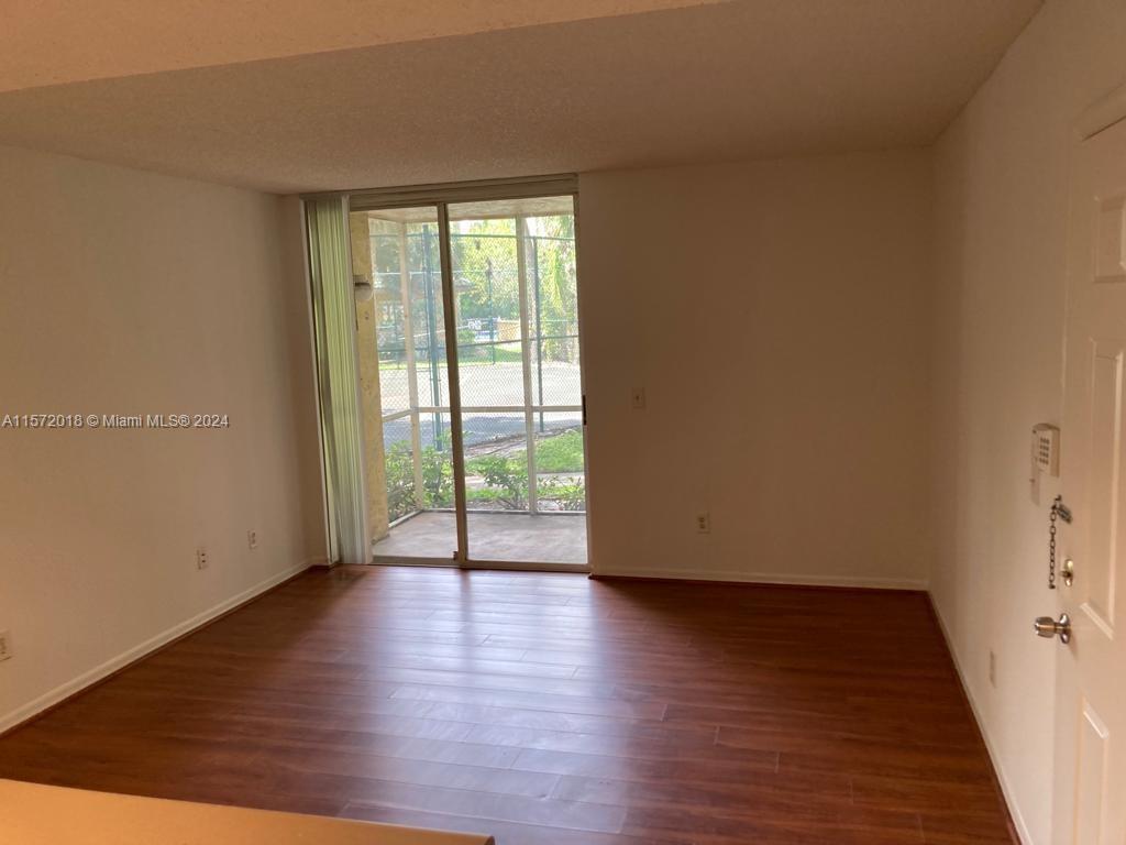3985 West McNab Road, Unit A111 Pompano Beach, FL 33069 - Photo 11 of 36 a view of an empty room with wooden floor and a window