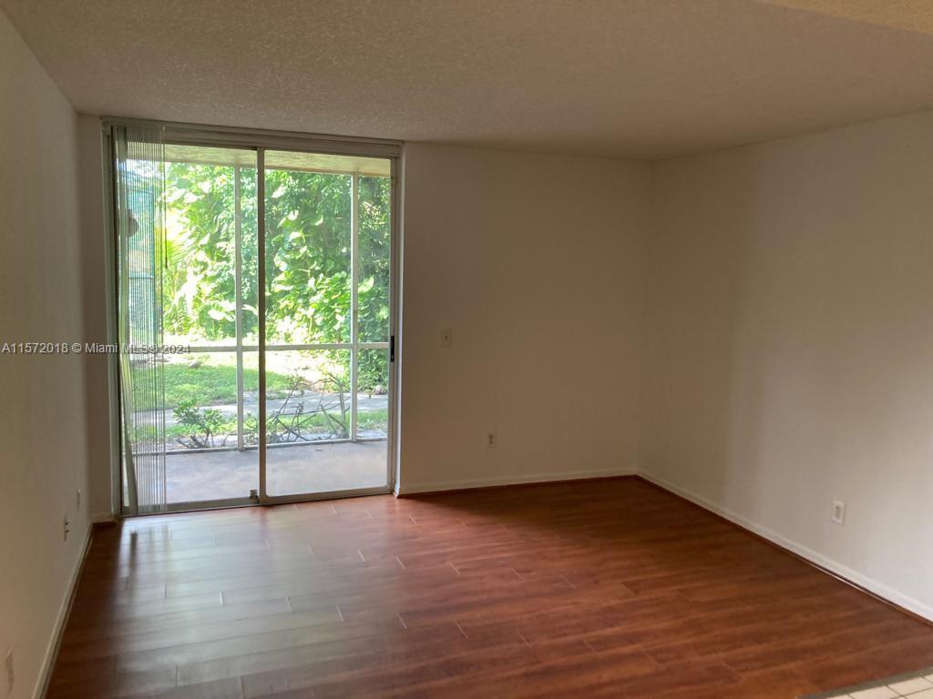 3985 West McNab Road, Unit A111 Pompano Beach, FL 33069 - Photo 13 of 36 a view of an empty room with wooden floor and a window