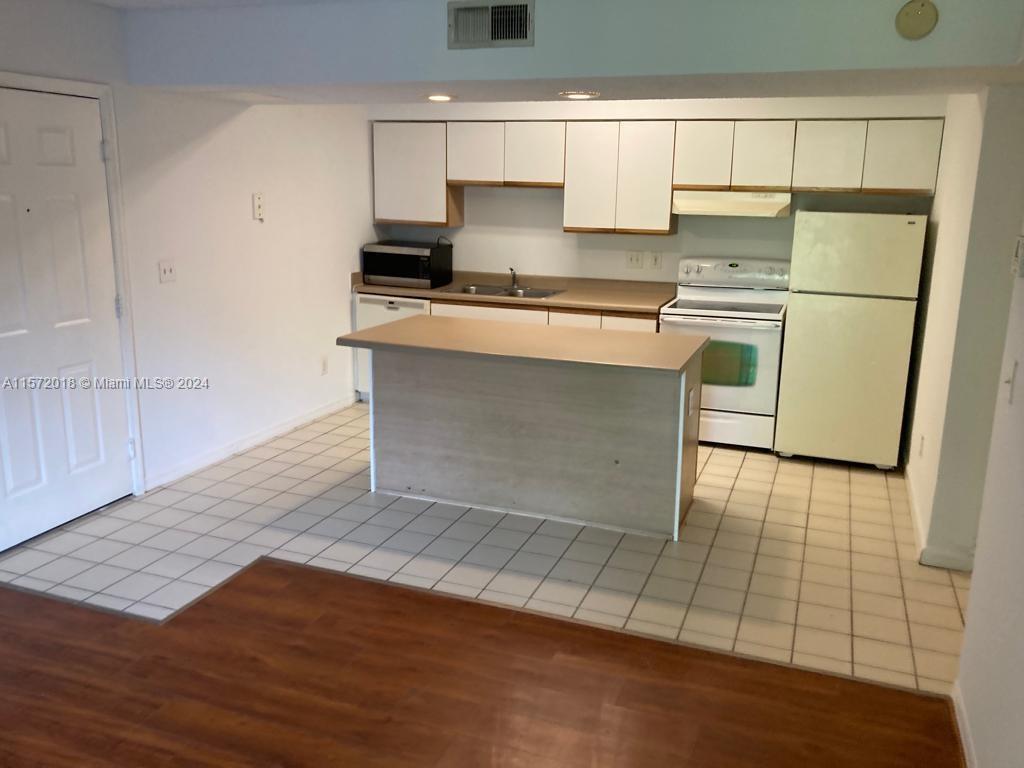 3985 West McNab Road, Unit A111 Pompano Beach, FL 33069 - Photo 4 of 36 a kitchen with kitchen island a stove a sink and a refrigerator