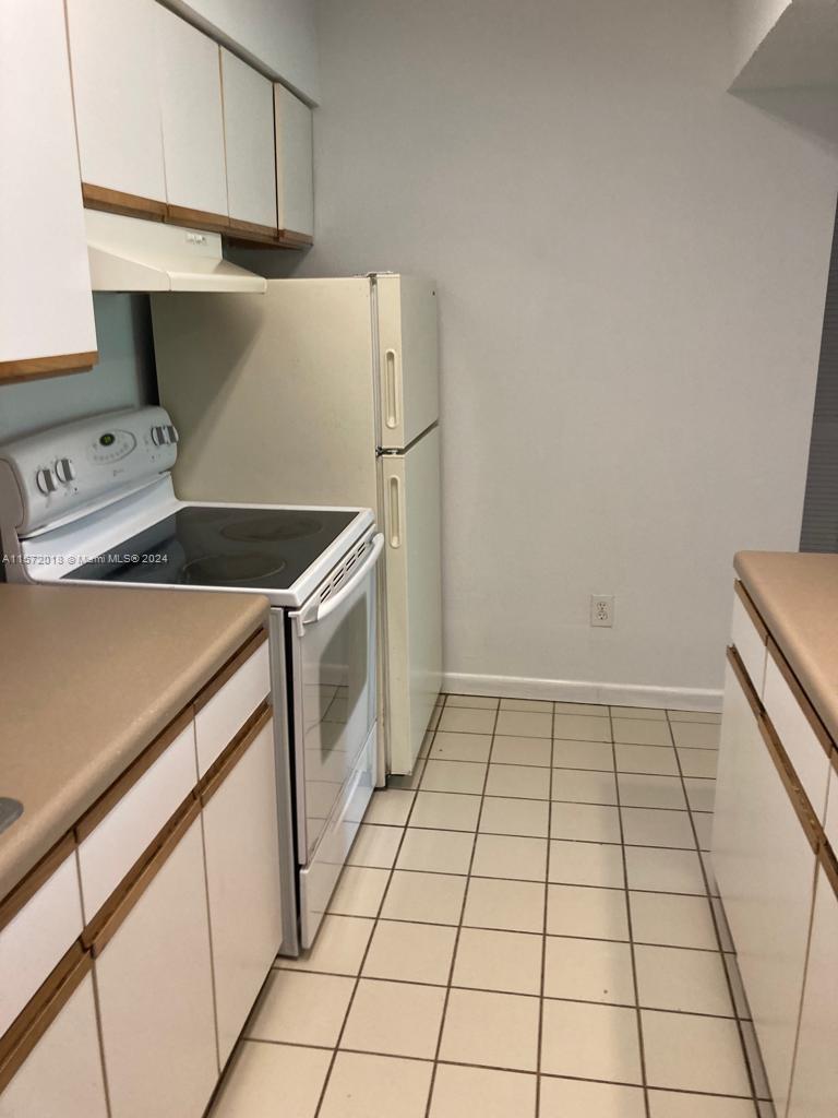 3985 West McNab Road, Unit A111 Pompano Beach, FL 33069 - Photo 7 of 36 a kitchen with a stove top oven and cabinets