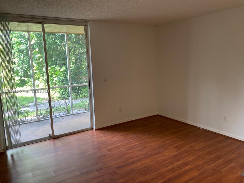 3985 West McNab Road, Unit A111 Pompano Beach, FL 33069 - Photo 10 of 36 a view of an empty room with wooden floor and a window