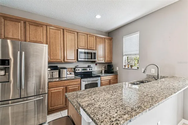 a kitchen with stainless steel appliances granite countertop a refrigerator stove microwave and sink