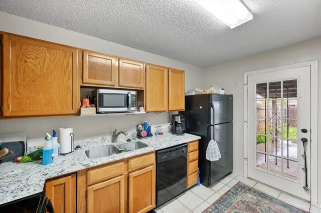 a kitchen with granite countertop a refrigerator a sink a stove and cabinets