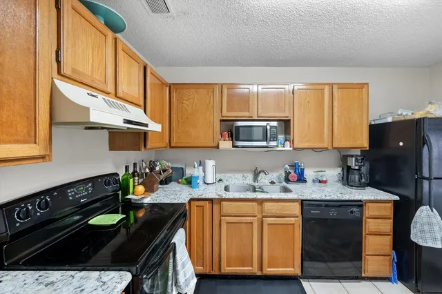 a kitchen with stainless steel appliances a stove a sink cabinets and a window