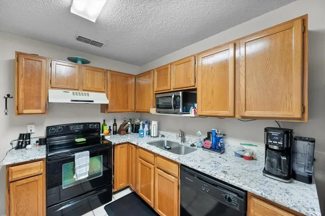 a kitchen with granite countertop a sink a stove cabinets and a window