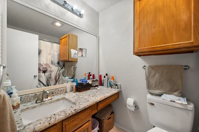 a bathroom with a granite countertop sink mirror vanity and toilet