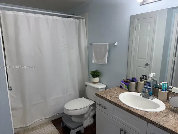 a bathroom with a granite countertop sink toilet and a mirror