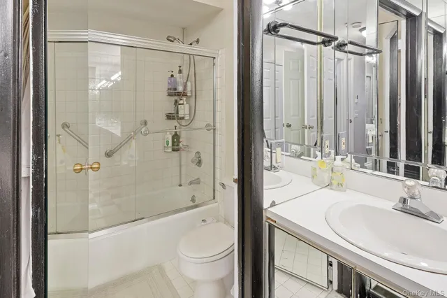 a bathroom with a granite countertop sink toilet and shower glass cabinet