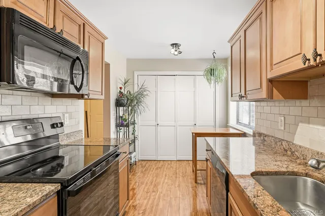 a kitchen with stainless steel appliances granite countertop a sink a stove and a microwave