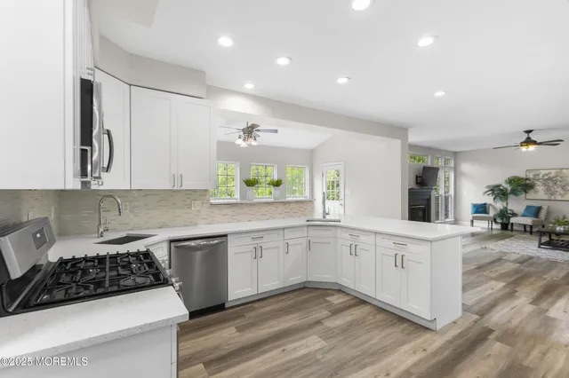 a kitchen with stainless steel appliances granite countertop a stove a sink a refrigerator and a dining table with wooden floor