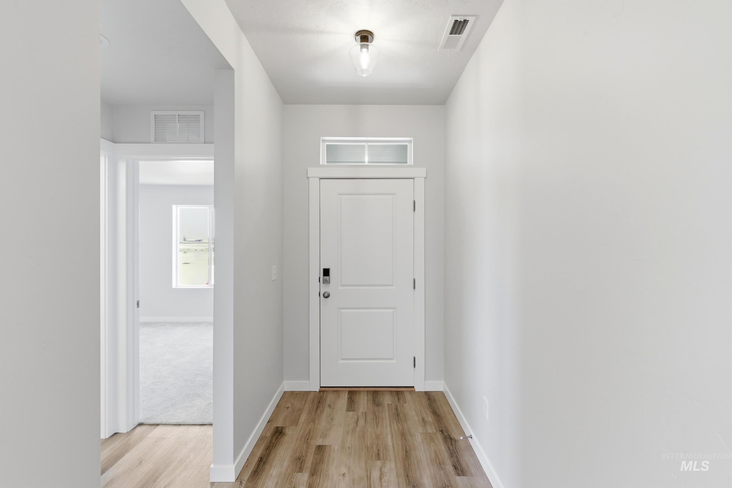 8317 South Tyrion Way Kuna, ID 83634 - Photo 2 of 22 Entryway featuring wood-finish flooring and a white paneled door with a transom window