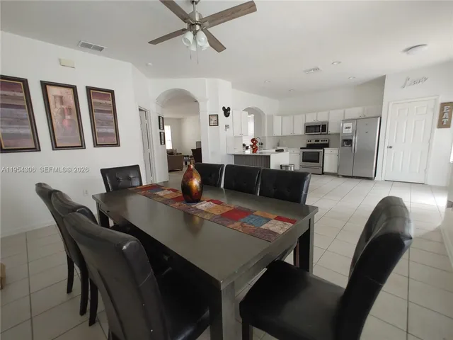 a open dining room with stainless steel appliances kitchen island granite countertop a sink a table and chairs