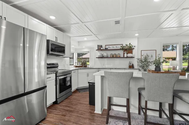 a kitchen with granite countertop a sink stainless steel appliances and white cabinets