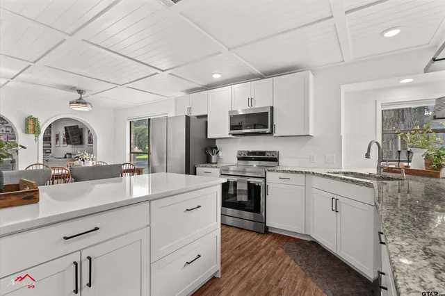 a view of kitchen with stainless steel appliances granite countertop a sink a stove a refrigerator cabinets and chairs