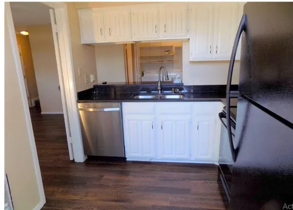 a kitchen with granite countertop a sink cabinets and wooden floor