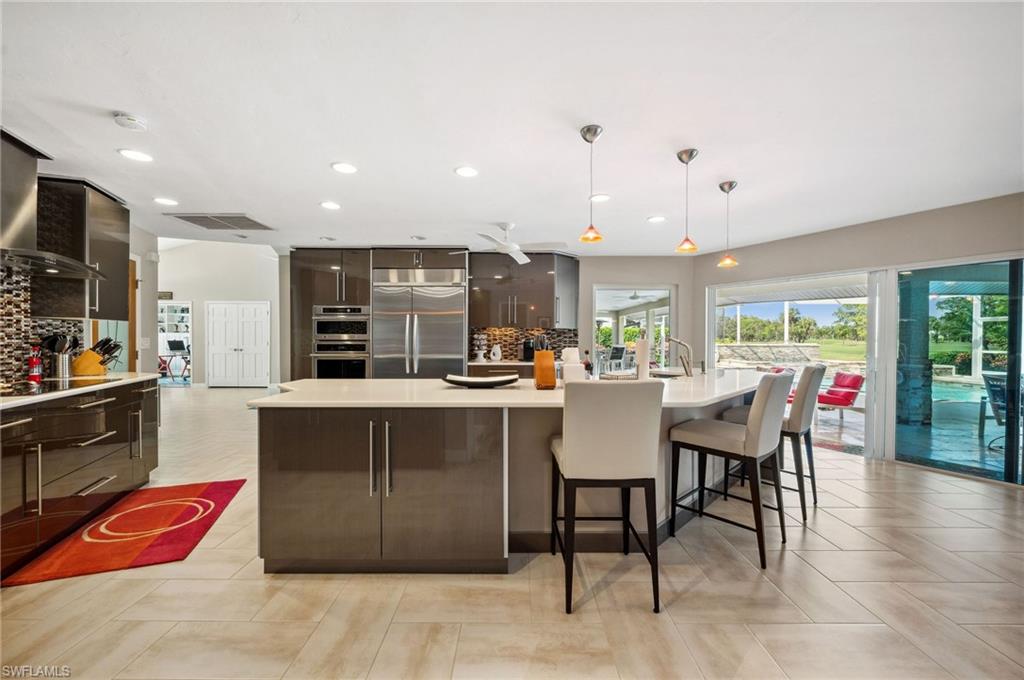 2104 Imperial Golf Course Boulevard Naples, FL 34110 - Photo 4 of 32 a kitchen with stainless steel appliances granite countertop a table chairs sink and cabinets