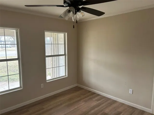 an empty room with chandelier fan and windows