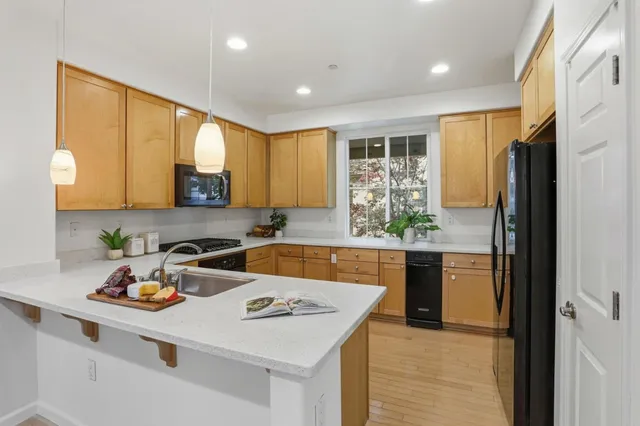 a kitchen with a refrigerator a stove a sink dishwasher with wooden cabinets and dining table with wooden floor