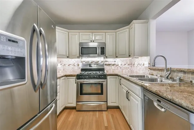 a kitchen with stainless steel appliances granite countertop a stove a sink and a refrigerator