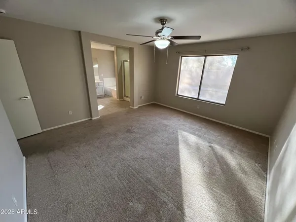 an empty room with windows and fan