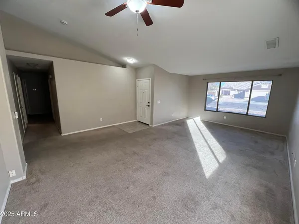 an empty room with chandelier fan and windows