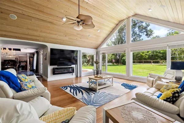 a view of a livingroom with furniture a fireplace wooden floor and chandelier