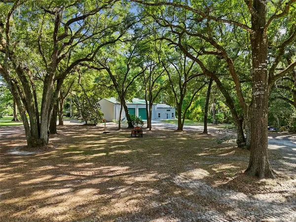 an aerial view of a house with swimming pool big yard and large trees
