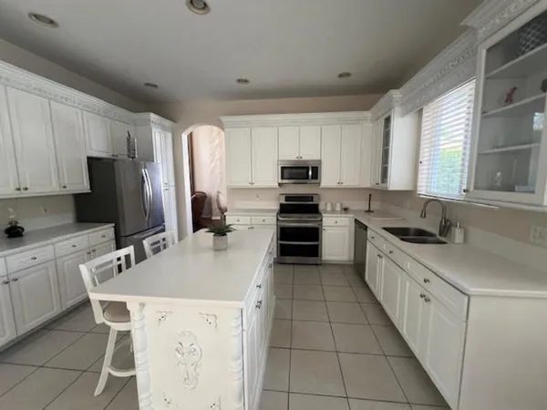 a kitchen with kitchen island granite countertop a sink counter top space appliances and cabinets