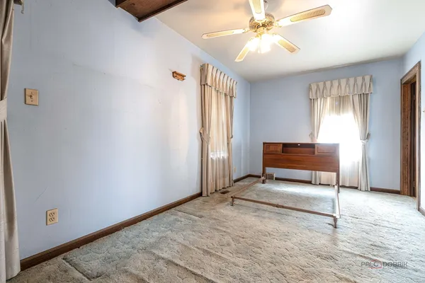 a view of an empty room with window and chandelier fan
