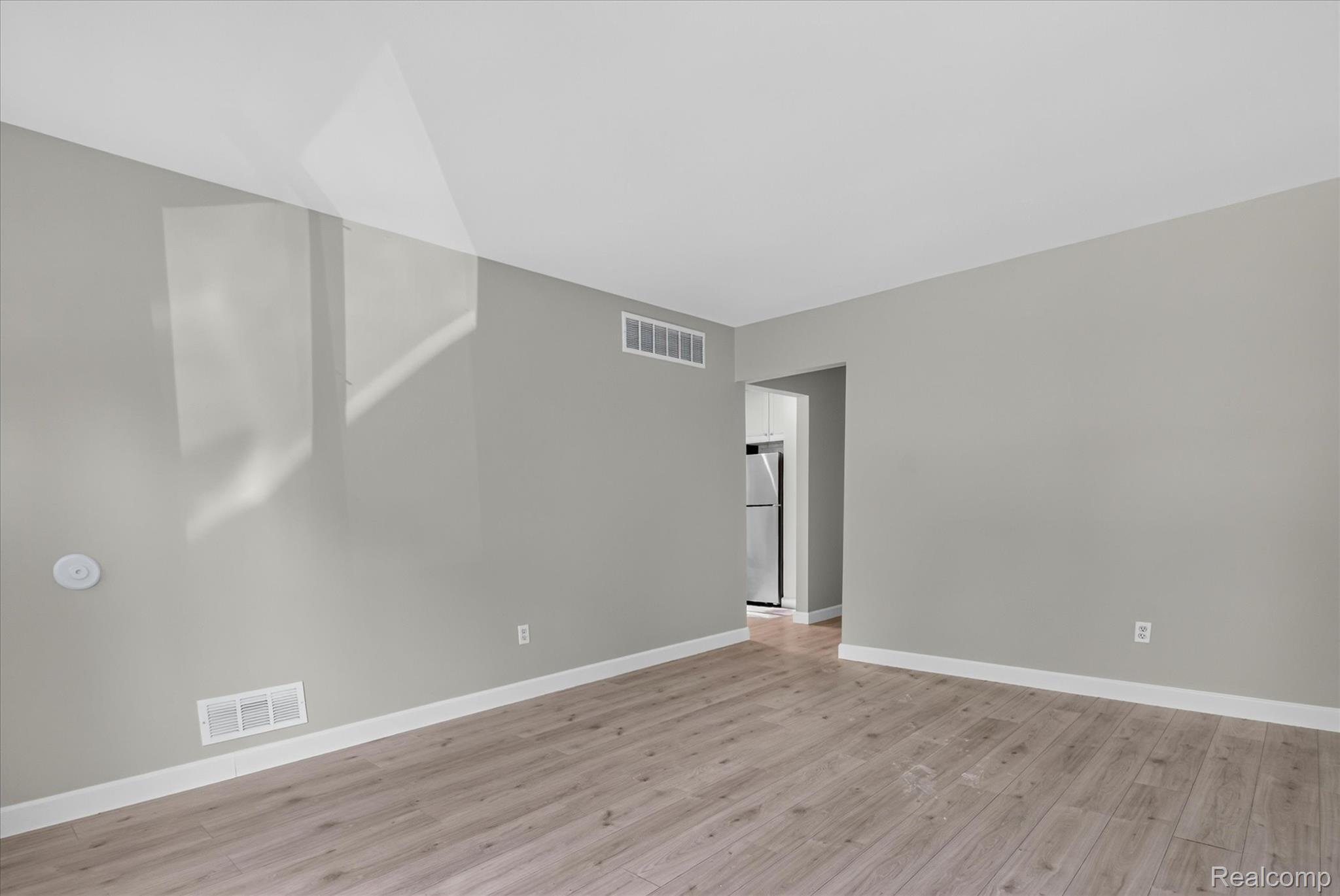 934 Harvard Road Berkley, MI 48072 - Photo 7 of 34 Spacious room featuring wood-finish flooring, light grey wall paint, white baseboards, and a white ceiling