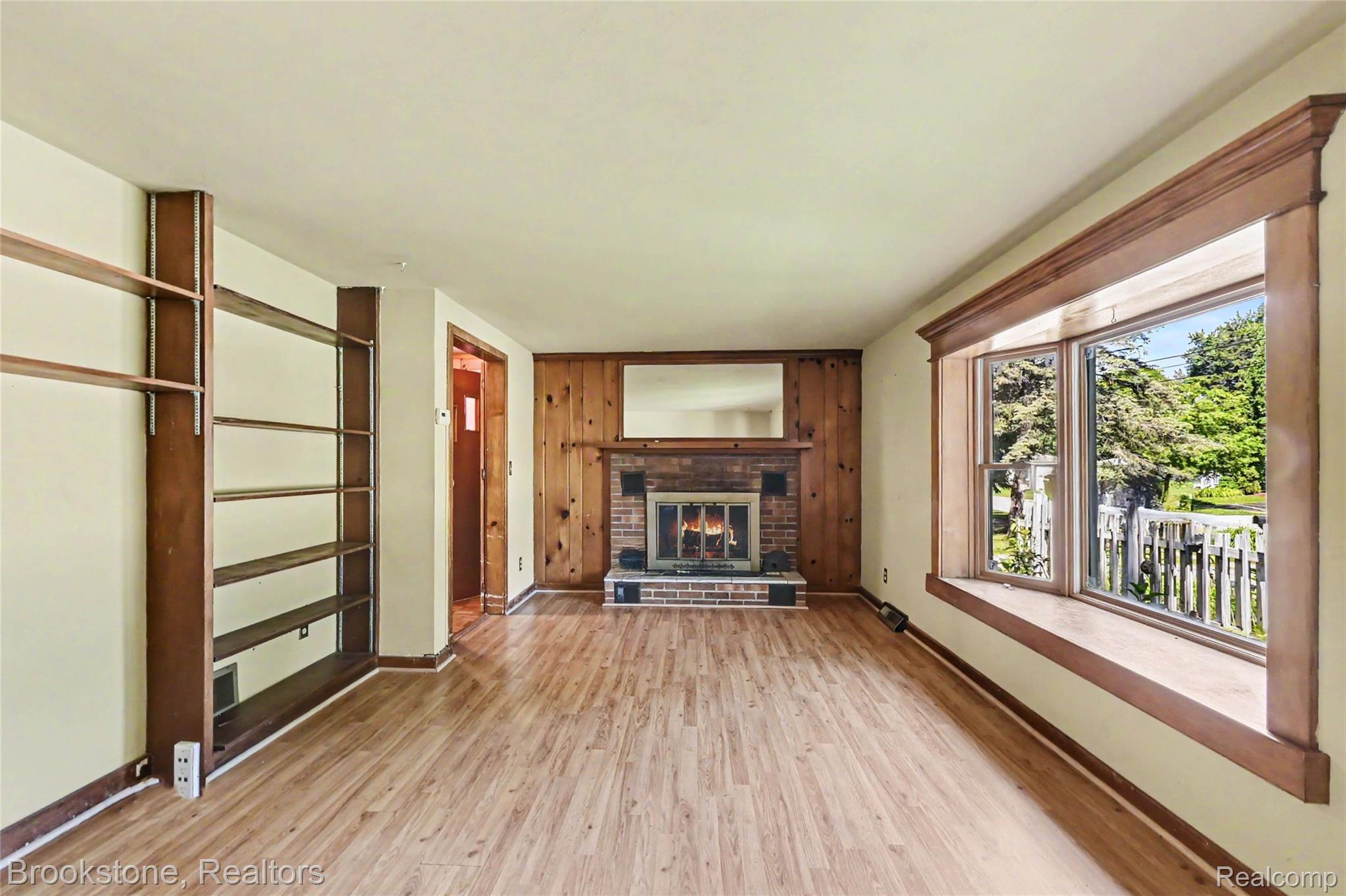 416 East Maple Street Mason, MI 48854 - Photo 3 of 18 Living area featuring wood-finish flooring, a brick fireplace with a wood mantle, and extensive built-in shelving