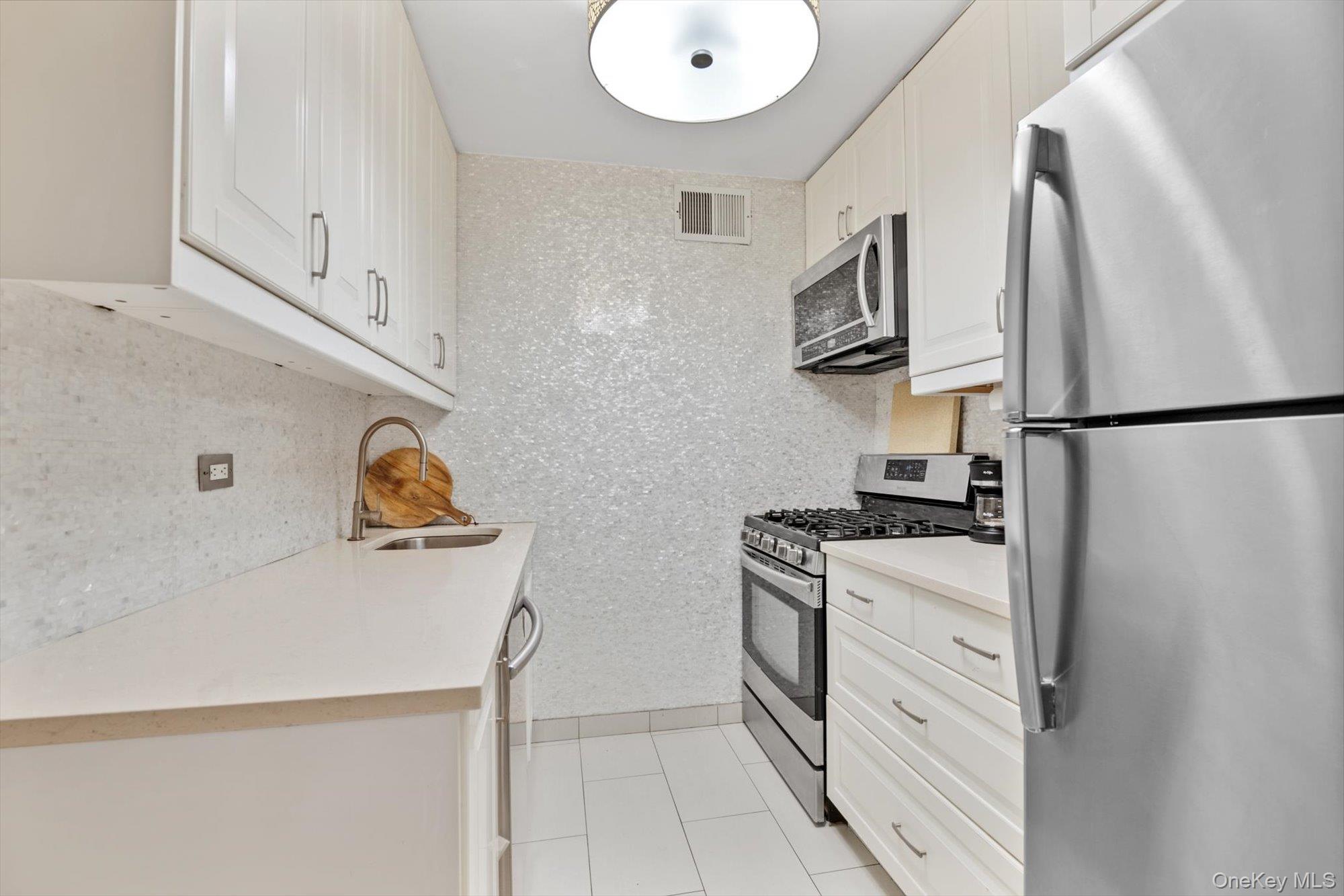 102-30 66th Road, Unit A28 Queens, NY 11375 - Photo 10 of 24 a kitchen with stainless steel appliances a refrigerator stove and sink