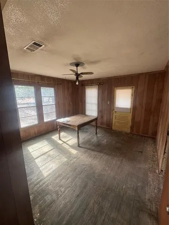 an empty room with windows and ceiling fan