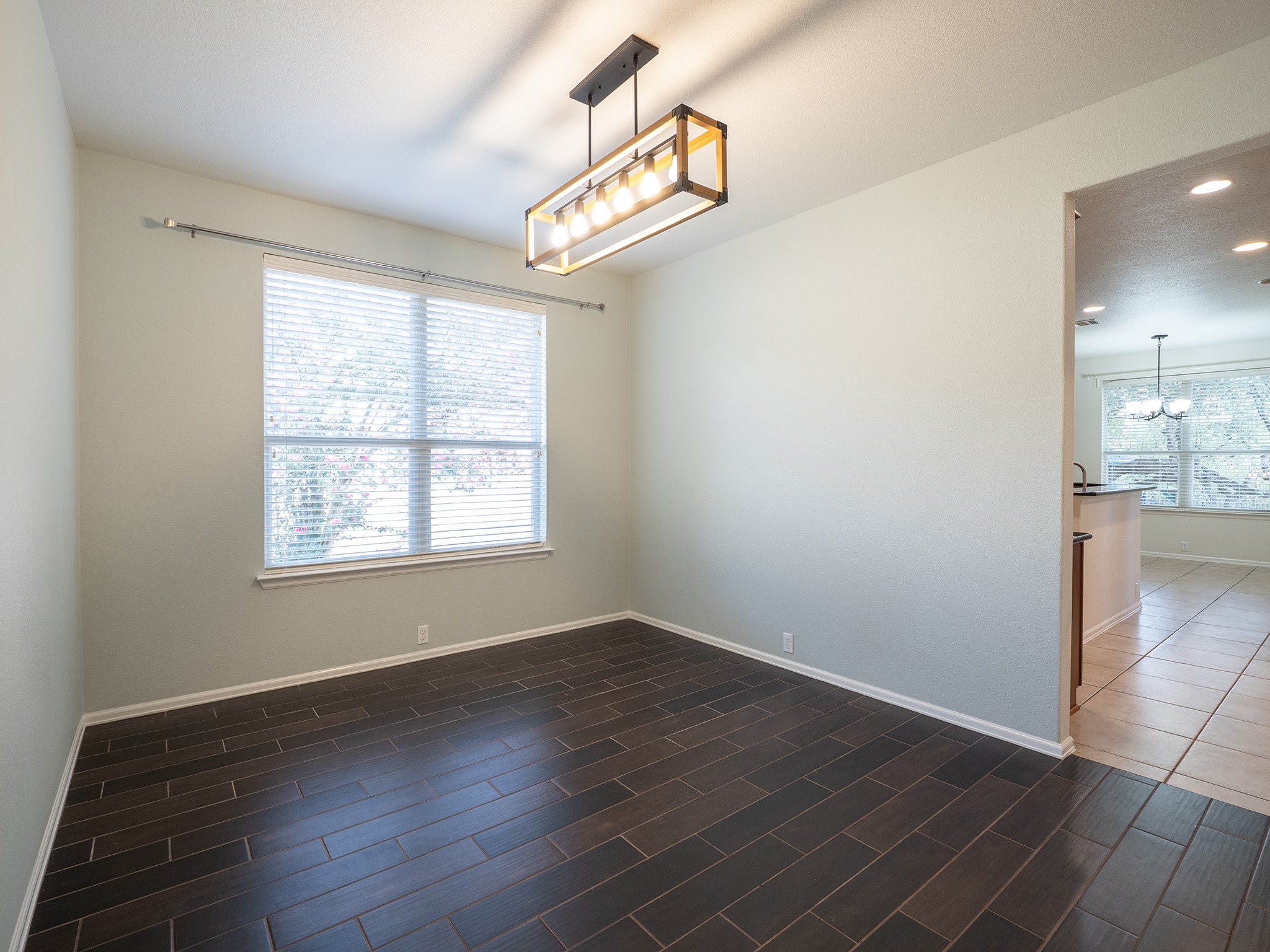 572 Big Meadow Road Austin, TX 78737 - Photo 9 of 32 Hardwood floors complement an open concept dining area featuring a modern rectangular chandelier.