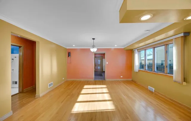 a view of an empty room with window and wooden floor