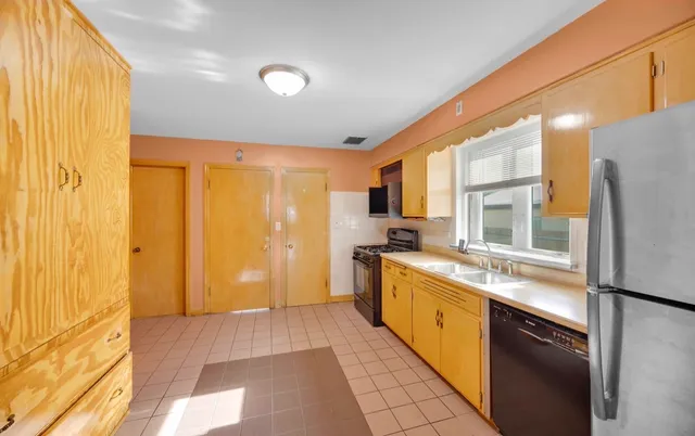 a large kitchen with stainless steel appliances granite countertop a refrigerator a stove and a sink with wooden floor