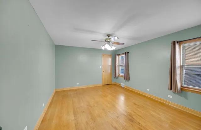 a view of a big room with windows and chandelier fan