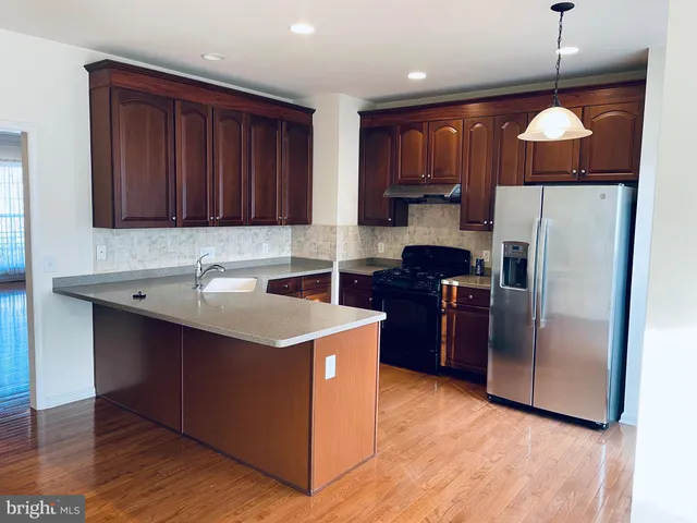 a kitchen with stainless steel appliances granite countertop a refrigerator a stove and a sink with wooden floors