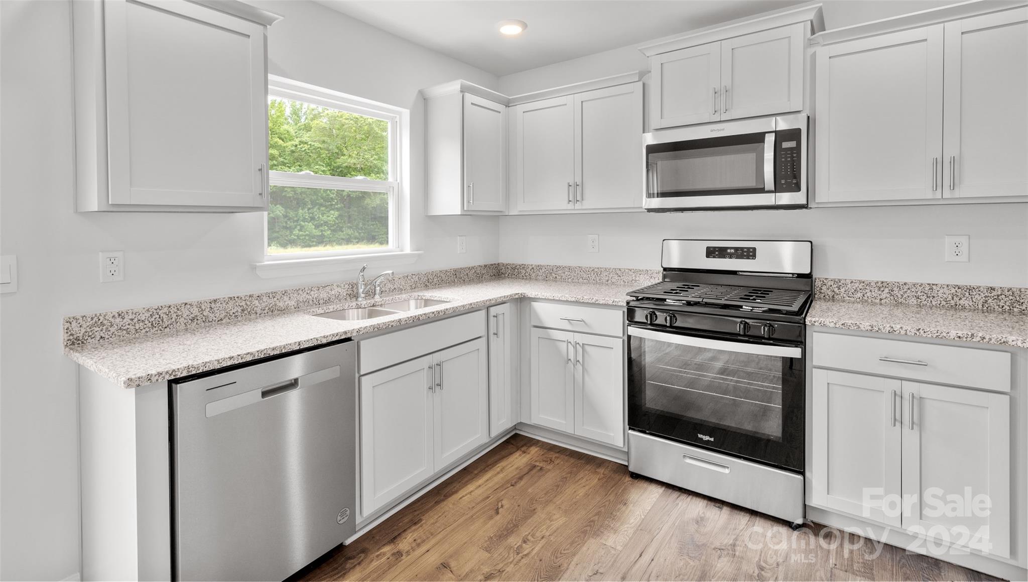 61 Callie River Clyde, NC 28721 - Photo 4 of 23 a kitchen with granite countertop white cabinets stainless steel appliances a sink and a window