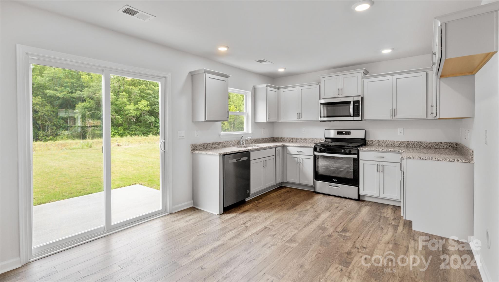 61 Callie River Clyde, NC 28721 - Photo 5 of 23 a kitchen with kitchen island granite countertop a stove a sink and white cabinets