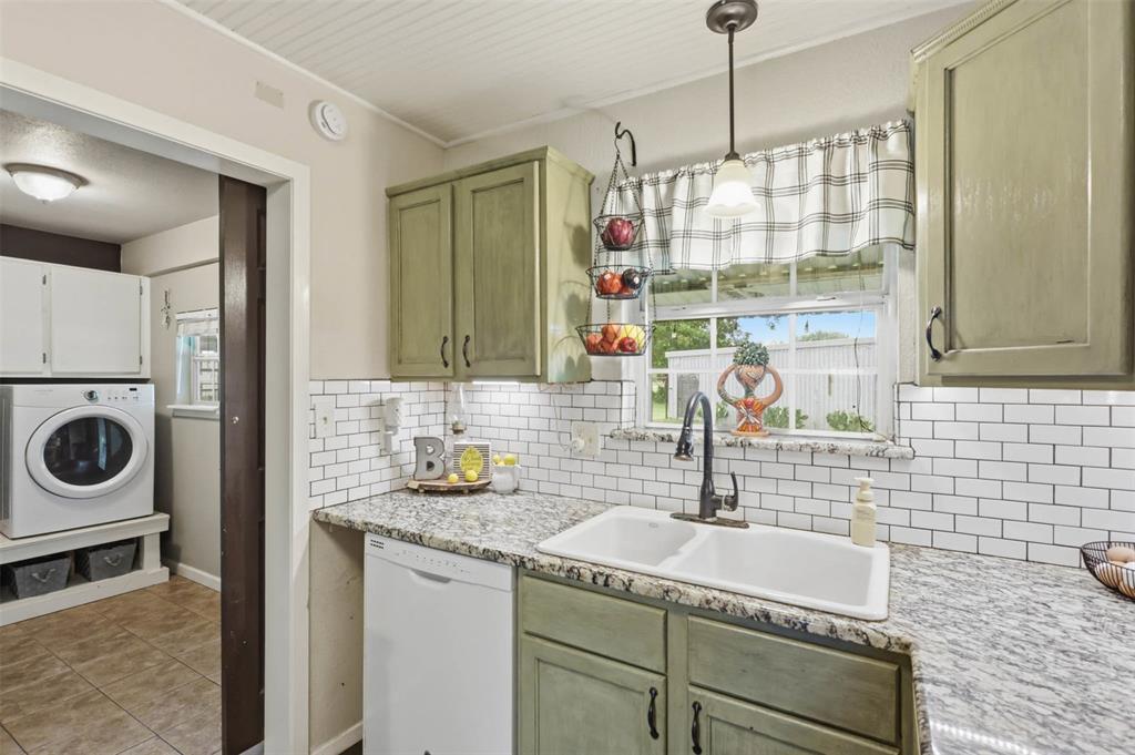 308 West 1st Street Springtown, TX 76082 - Photo 15 of 39 Kitchen with light green cabinetry, granite countertops, white subway tile backsplash, and a double basin sink with a black gooseneck faucet