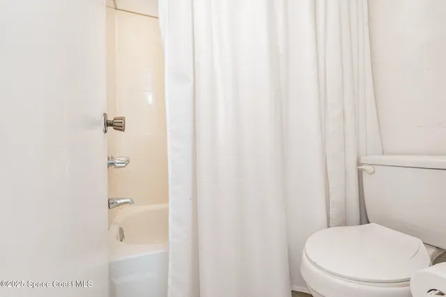 a white toilet sitting next to a shower