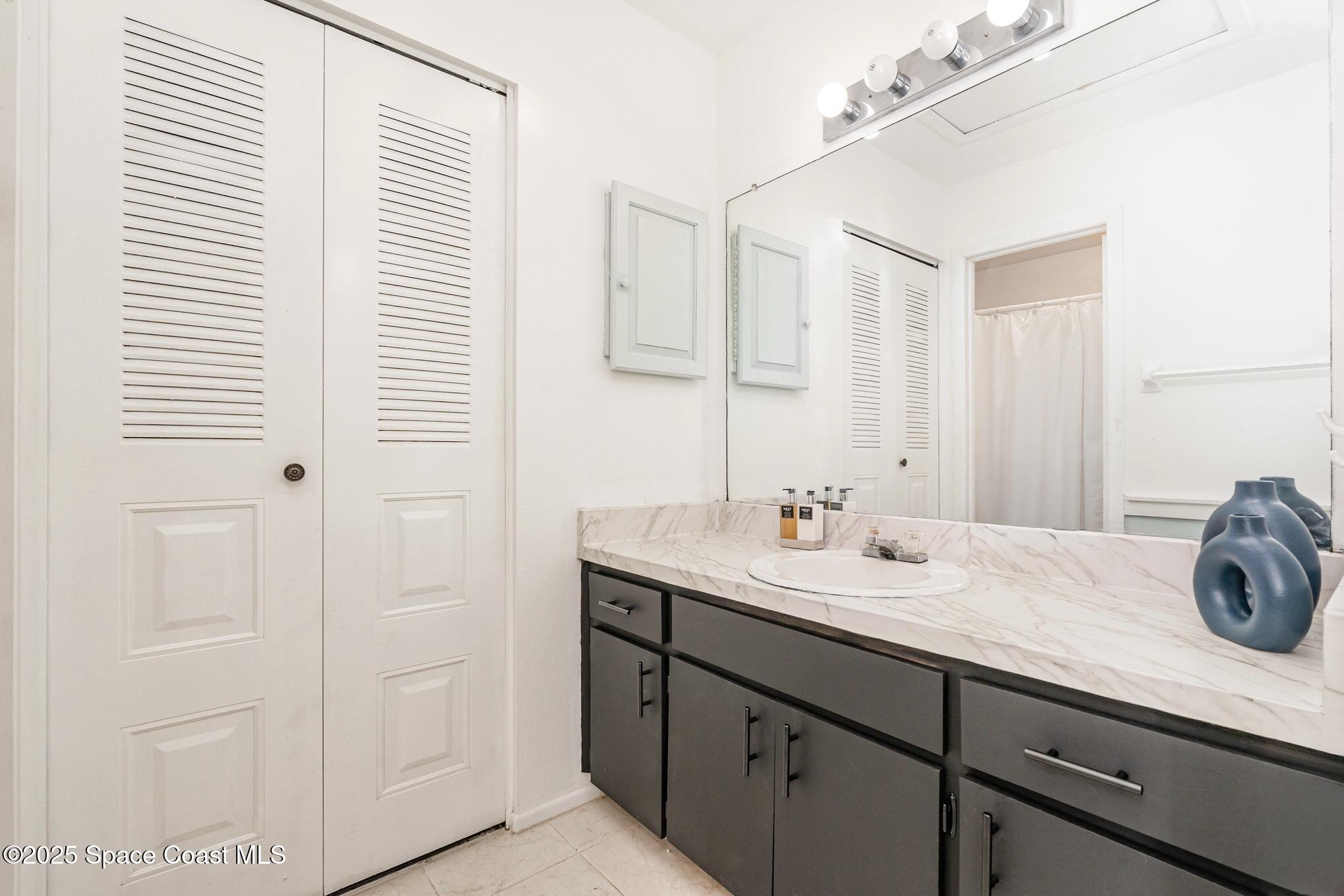 1411 Sheafe Avenue Northeast, Unit 101 Palm Bay, FL 32905 - Photo 13 of 25 a bathroom with a granite countertop sink and a mirror