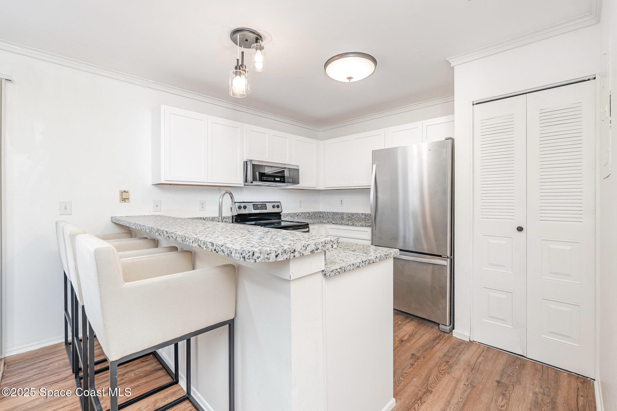 1411 Sheafe Avenue Northeast, Unit 101 Palm Bay, FL 32905 - Photo 9 of 25 a kitchen with kitchen island a counter top space cabinets and stainless steel appliances