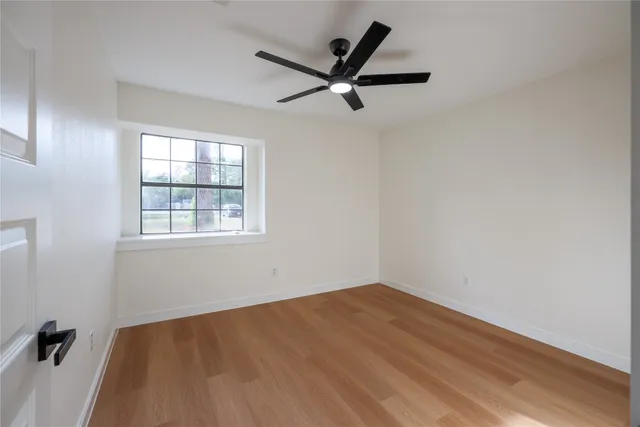 an empty room with a window and a ceiling fan
