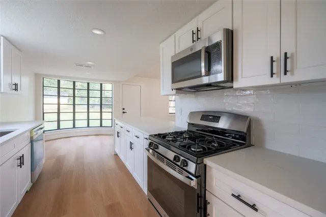 a kitchen with stainless steel appliances a stove a microwave and cabinets