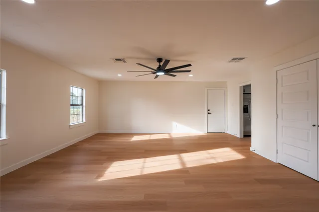 a view of empty room with wooden floor and fan