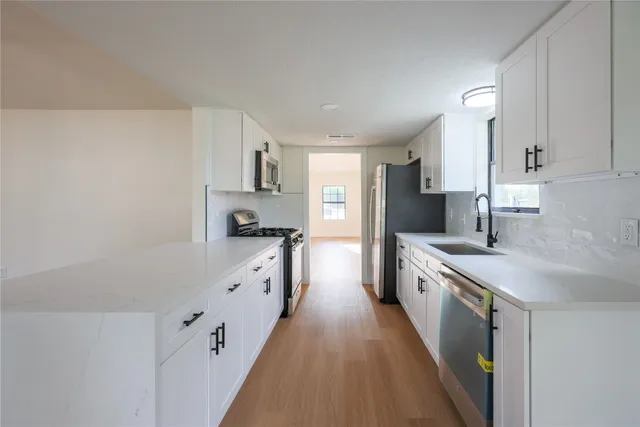 a kitchen with granite countertop a sink a stove refrigerator and cabinets